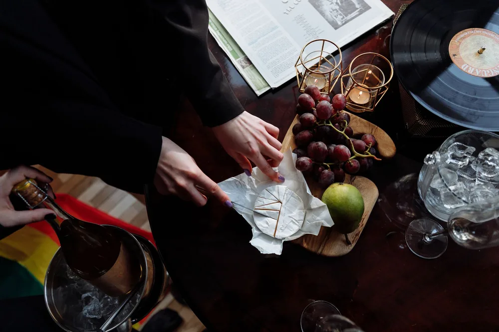 Top view of an elegant table setup featuring cheese, wine, and grapes, creating a cozy mood