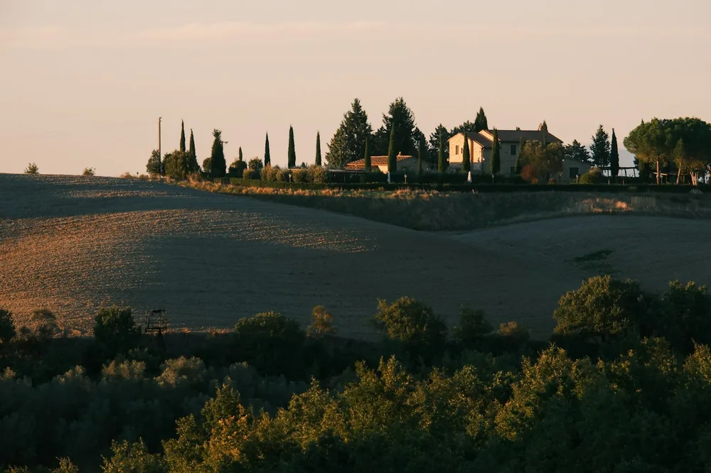 Tuscan farmhouse on rolling hills at sunset