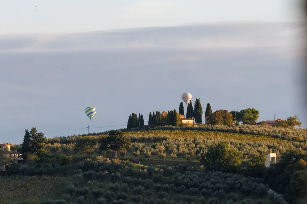 Tuscan hills with hot air balloons during a serene day