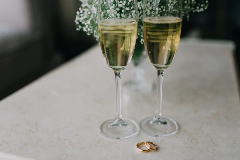 Two champagne glasses and wedding rings on a table, perfect for celebrations