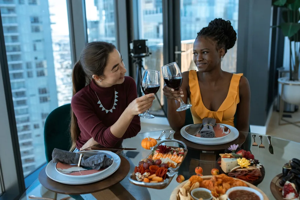 Two friends toast with wine over a beautifully arranged charcuterie and cheese platter