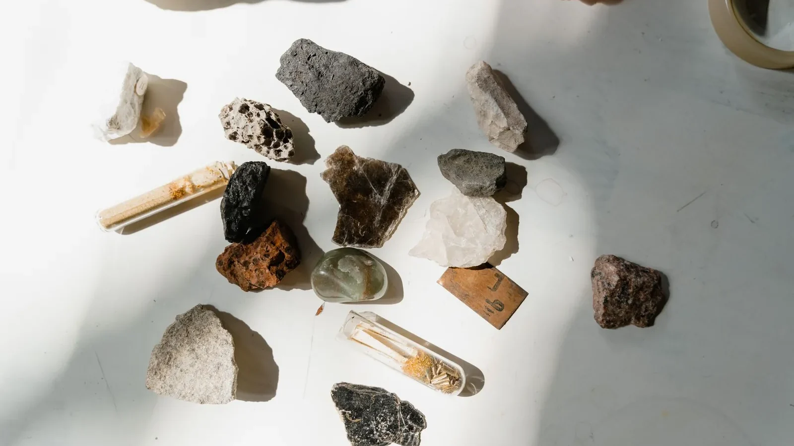 Various minerals and rocks arranged on a sunlit table, showcasing natural textures and colors