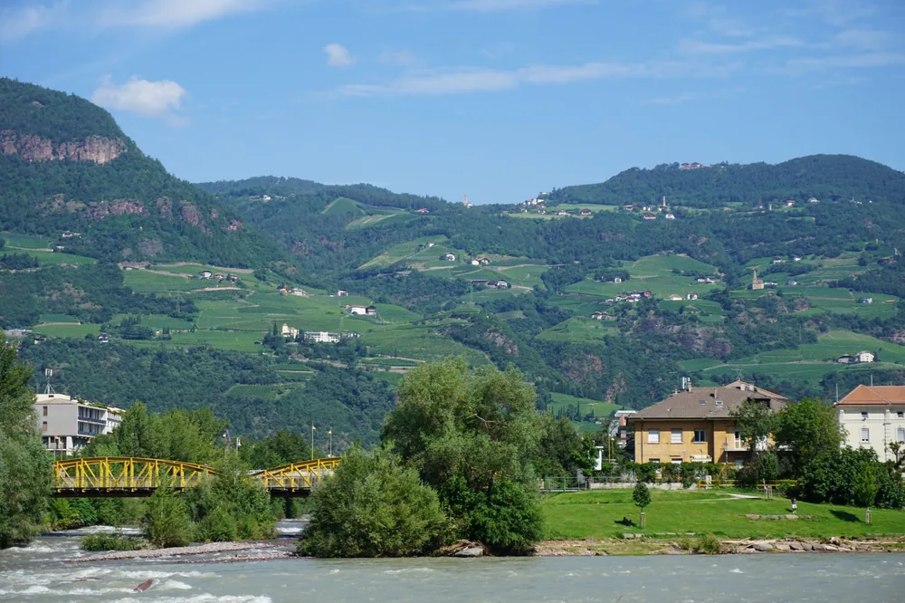 Village nestled in lush green hills with trees and a flowing river
