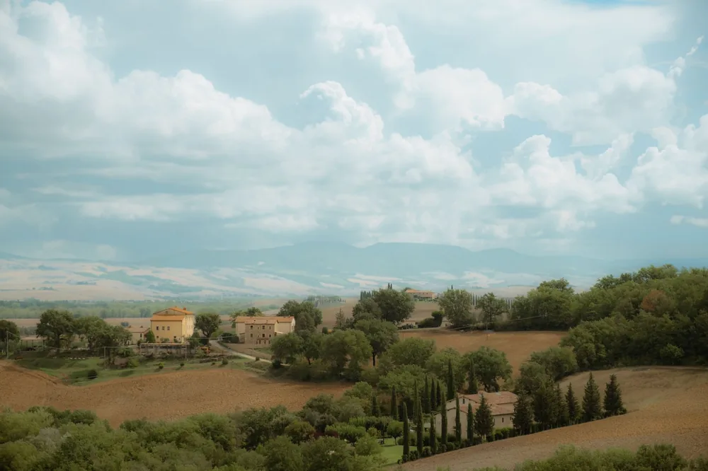 Village nestled in lush rolling hills under a dramatic cloudy sky