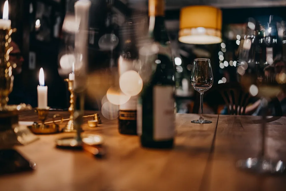 Warm, inviting restaurant scene with wine glasses and candles on a wooden table creating a cozy atmosphere