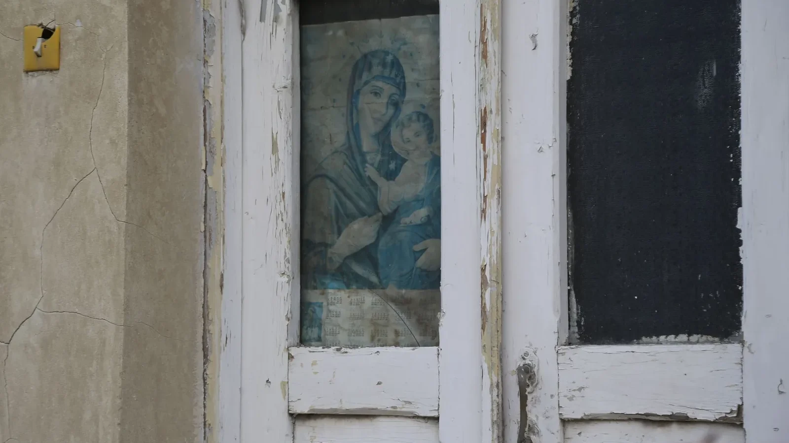 Weathered door with religious artwork and crackled paint, offering vintage charm