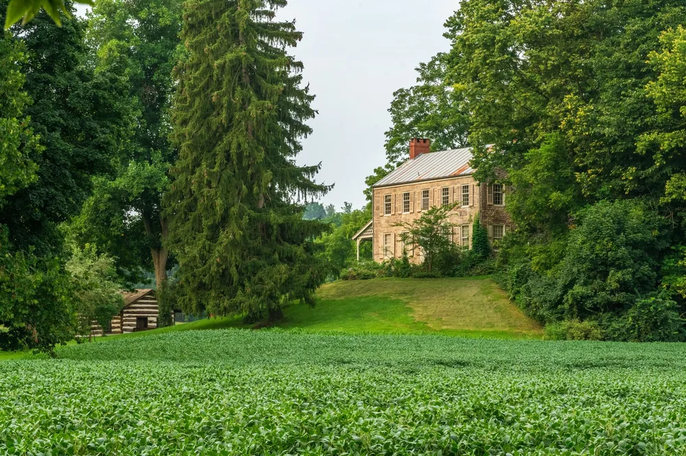 Well-preserved farmhouse surrounded by lush greenery and fields, evoking rustic charm and tranquility