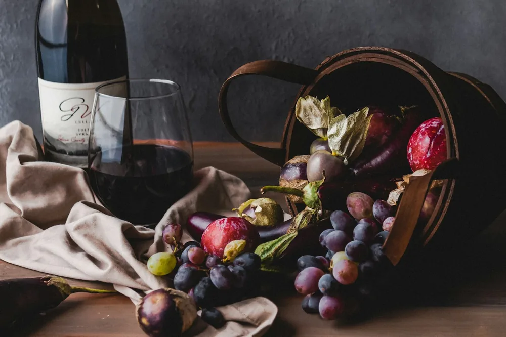 Wine glass beside grapes and wine glass on table