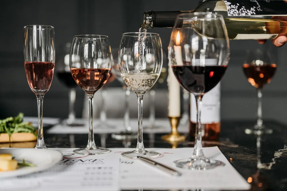 Wine tasting setup with various wines being poured into glasses indoors