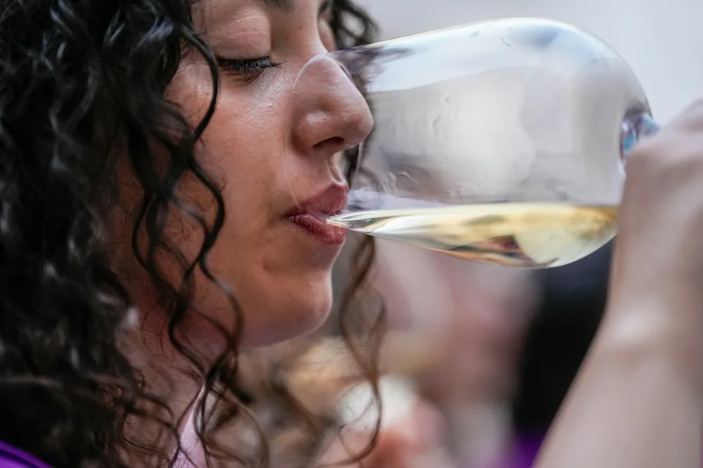Woman with curly hair drinking white wine from a glass