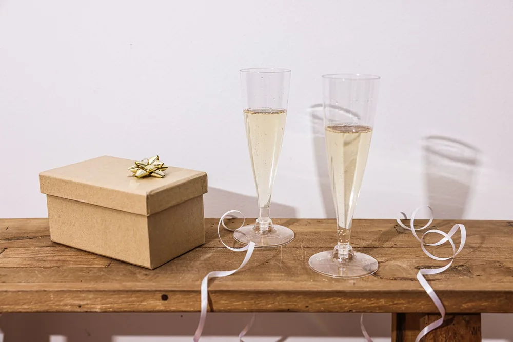 Wooden table setup with champagne glasses and a gift box for a special celebration occasion